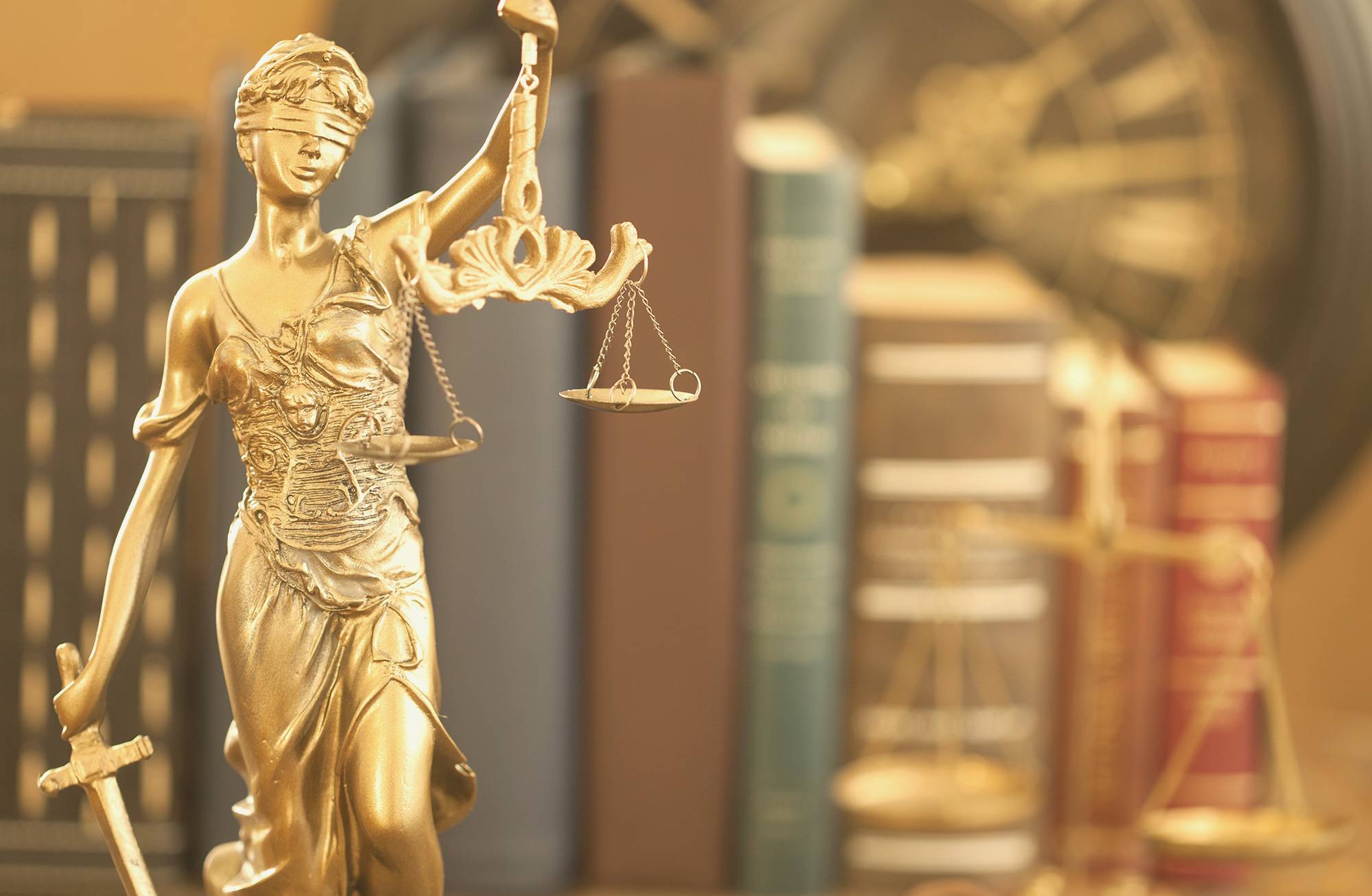 Gold statue wearing a blindfold holding the scales of justice in one hand and a sword in the other